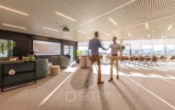 Moderne kantoorruimte te huur in Aalst met comfortabele zitplaatsen en zakelijke professionals die overleggen. Licht interieur en ruime opstelling aan de Korte Keppestraat 19 voor een inspirerende werkomgeving.