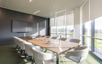Moderne vergaderruimte beschikbaar in Aalst op Korte Keppestraat 19, met een lange tafel, comfortabele stoelen en veel natuurlijk licht. Ideaal voor kantoorruimte te huur en zakelijke bijeenkomsten.