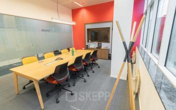 Vergaderruimte te huur in Antwerpen Berchem aan de Uitbreidingstraat 84 met lichte muren, lange houten tafel, comfortabele stoelen en moderne audiovisuele apparatuur.