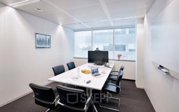 Vergaderruimte met moderne meubels in een kantoor te huur op Lange Lozanastraat 142, Antwerpen Centrum. De ruimte is voorzien van een grote tafel, stoelen en een scherm.
