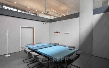 Modern kantoor te huur op Lange Winkelhaakstraat 26, Antwerpen Centrum, met een vergaderruimte die multifunctioneel is ingericht, voorzien van een lange tafel en comfortabele stoelen.