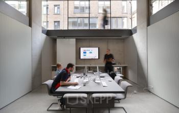 Vergaderruimte in modern kantoor te huur op Lange Winkelhaakstraat 26, Antwerpen Centrum met kantoormedewerkers aan het werk rondom een grote tafel.