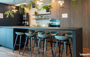 Moderne kitchenette in kantoorpand Nijverheidsstraat 70, Antwerpen Wommelgem, uitgerust met hoge barkrukken, koffieautomaat en planten.