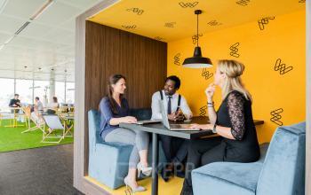 Gezellig ingerichte werkruimte in Brussel Airport op Leonardo Da Vincilaan 1, met diverse mensen die zakelijke gesprekken voeren.