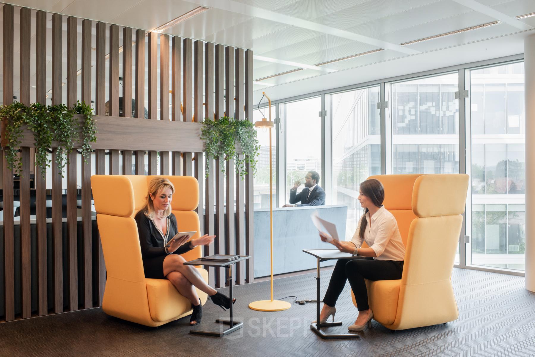 Moderne werkruimte in kantoor te huur op Leonardo Da Vincilaan 1, Brussel Airport, Brussel, met twee mensen die zakelijke gesprekken voeren in comfortabele stoelen.
