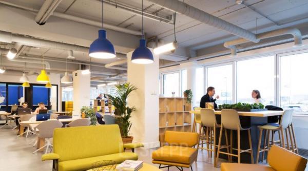 Moderne, lichtrijke kantoorruimte te huur op Pegasuslaan 5 in Brussel Airport, geschikt voor diverse werkactiviteiten. Verschillende personen voeren zakelijke gesprekken en werken aan tafels.