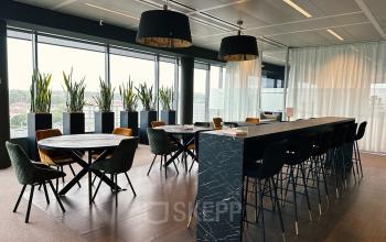 Koop of huur luxe kantoorruimte op Leonardo Da Vincilaan 19, Brussel Airport, met een lange tafel en hoge stoelen, ruime ramen en planten.