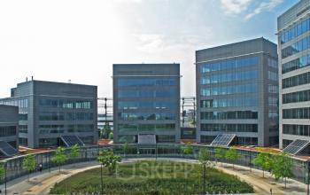 Exterieur van Leonardo Da Vincilaan 19 in Brussel Airport, een modern kantoorgebouw met glazen gevels en een groene binnenplaats. Kantoorruimte te huur beschikbaar.