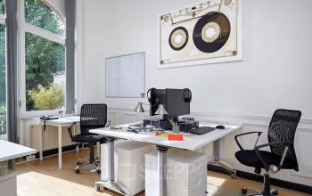 Kantoorruimte te huur in Brussel Airport, ingericht met bureaus, stoelen, computers, kunst aan de muur en veel natuurlijk licht.