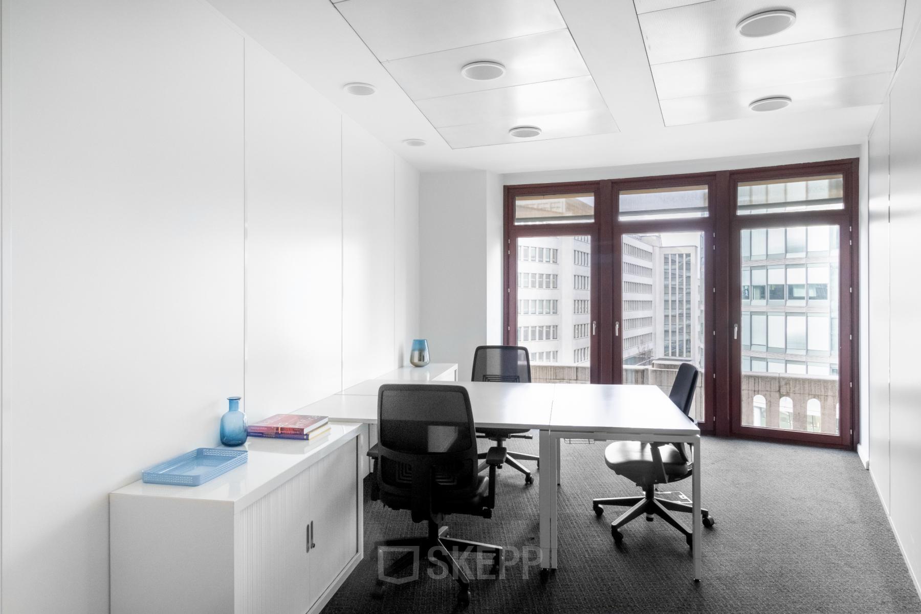 Kantoorruimte te huur in Brussel Centrum aan de Koloniënstraat / Rue des Colonies 11 met moderne inrichting, drie bureaus en stoelen, grote ramen en natuurlijk lichtinval.