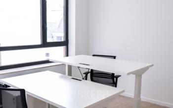 Lichte kantoorruimte te huur op Rue du Congres 37, Brussel met verstelbare bureaus, stoelen en een modern verlichtingsarmatuur.