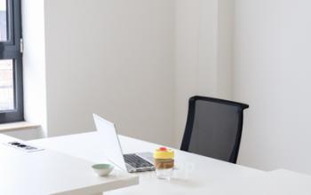 Kantoorruimte te huur op Rue du Congres 37 in Brussel, met een bureau, laptop, stoel en notitieboekjes.