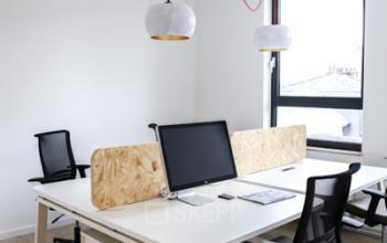 Moderne kantoorruimte te huur op Rue du Congres 37, Brussel, met bureaus, stoelen en computers, veel natuurlijk lichtinval door groot raam.