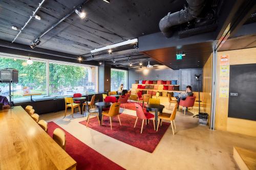 Koffiehoek en ontspanningsruimte in kantoor te huur op Louizalaan / Avenue Louise 523, Brussel Elsene. Mensen zitten aan tafels in gesprek, ingericht met kleurrijke stoelen en banken.