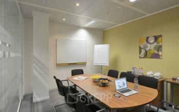 Modern ingerichte vergaderruimte voorzien van een grote tafel, comfortabele stoelen en diverse versnaperingen, gelegen op Schumanplein in Brussel. Ideaal voor wie kantoorruimte wil huren.