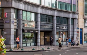 Kantoor te huur aan Schumanplein, Brussel Etterbeek. Mensen zijn onderweg of in gesprek voor de ingang van het gebouw.