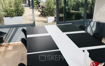 Vergaderruimte te huur op Priester Cuypersstraat / Rue Abbé Cuypers 3, Brussel Etterbeek, met een grote tafel, stoelen en natuurlijk licht.