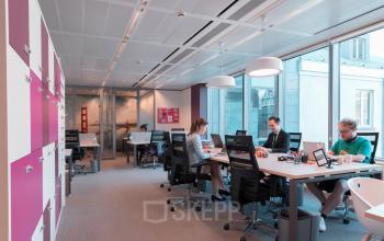 Kantoorruimte te huur op Meeûssquare / Square de Meeûs 38-40 in Brussel Europese Wijk. Drie mensen bezig met zakelijke activiteiten in een moderne werkruimte met bureaus en stoelen.