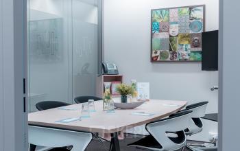 Vergaderruimte te huur op het kantoor gelegen op Meeûssquare / Square de Meeûs 38-40, in de Europese Wijk, Brussel. Moderne ruimte met vergadertafel, stoelen en kunst aan de muur.