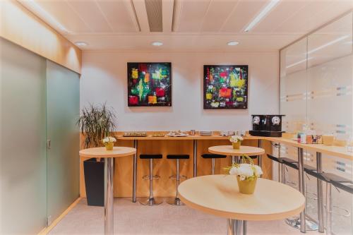 Foto van een gemeubileerde kantoorruimte te huur in Meeûssquare / Square de Meeûs 38-40, Europese Wijk, Brussel. De ruimte heeft hoge tafels en schilderijen aan de wand.