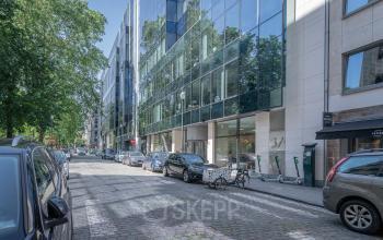 Modern kantoorgebouw te huur gelegen op Meeûssquare / Square de Meeûs 37 in de Europese Wijk, Brussel. Glazen gevel reflecteert omgeving.