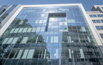 Modern kantoorgebouw aan Meeûssquare / Square de Meeûs 37 in de Europese Wijk, Brussel, met spiegelende glazen gevel en meerdere verdiepingen kantoorruimte te huur.