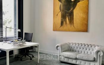 Kantoorruimte te huur op Rue d’Arlon 25 in Brussel Europese Wijk, modern ingericht met een bureau, zwarte stoel en witte sofa, verlicht door natuurlijk licht.