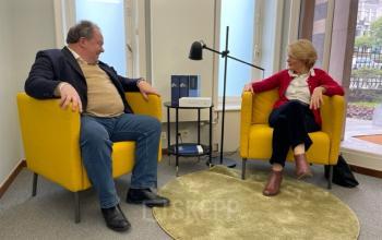 Kantoorruimte te huur op Avenue Palmerston 3, Brussel Europese Wijk, met twee personen in zakelijke bespreking in een ruimte met gele stoelen en een ronde groene mat.