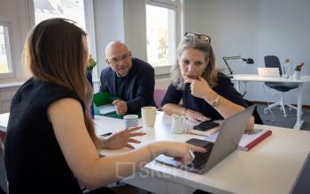 Drie collega’s zijn in overleg in een lichte kantoorruimte met grote ramen op Avenue Palmerston 3, Europese Wijk, Brussel, waar kantoorruimte te huur is.