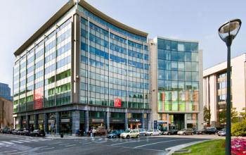 Zakelijk kantoorgebouw op het Robert Schumanplein 2-4 in Brussel Europese Wijk, met moderne glazen gevels en omringd door wegen en auto's, beschikbaar voor kantoor te huur.