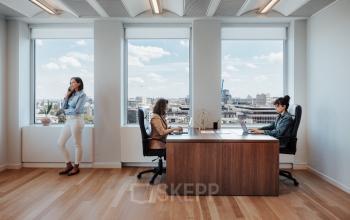 Kantoorruimte te huur op Robert Schumanplein 2-4 in Brussel Europese Wijk met drie personen die werken aan bureaus met uitzicht op de stad.