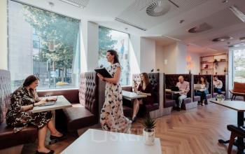 Zakelijke professionals werken samen in een gemeubileerde kantoorruimte te huur op Robert Schumanplein 2-4, Brussel Europese Wijk, met comfortabele zitplaatsen en veel natuurlijk licht.