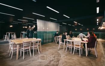 Moderne kantoorruimte te huur op Meeûssquare / Square de Meeûs 35, Brussel Europese Wijk, met werknemers aan grote houten tafels bezig met laptops.