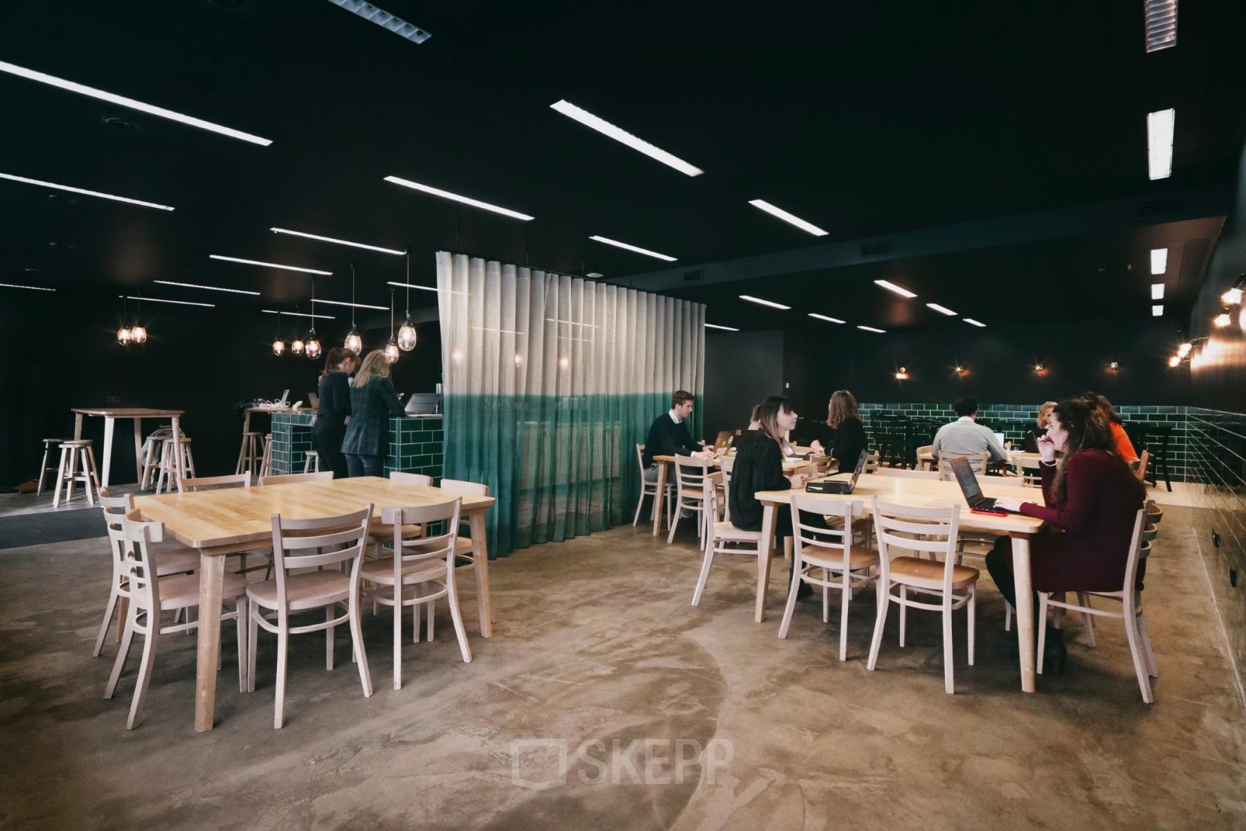 Moderne kantoorruimte te huur op Meeûssquare / Square de Meeûs 35, Brussel Europese Wijk, met werknemers aan grote houten tafels bezig met laptops.