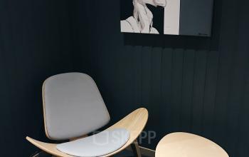 Kantoor te huur aan de Breydelstraat/Rue Breydel 34-36 in Brussel Europese Wijk met een moderne stoel, bijzettafel en kunstwerk aan de muur.