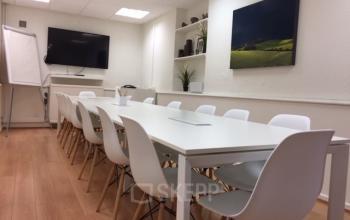 Kantoorruimte te huur in Brussel Europese Wijk, Breydelstraat 34-36 met moderne vergadertafel, whiteboard, flatscreen tv en kunst aan de muur.