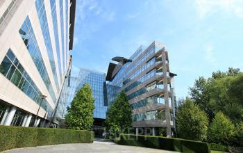 Kantoor te huur gelegen aan Woluwedal 18-22, Brussel Sint-Stevens-Woluwe, moderne glazen gevels en omgeven door groen.