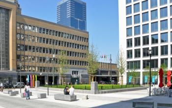 Foto van een open buitenruimte op Place Marcel Broodthaers 8, Brussel Zuid, met moderne gebouwen en bankjes. Kantoorruimte te huur in een levendige omgeving.