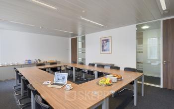 Vergaderruimte op Place Marcel Broodthaers 8, Brussel Zuid met houten tafel, stoelen, laptop en fruit. Kantoorruimte te huur met diverse voorzieningen.