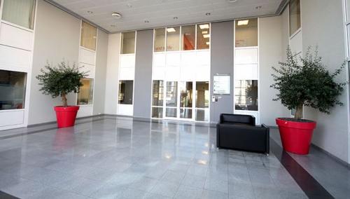 Moderne ingang van kantoor te huur op Pontbeekstraat 2-4 in Dilbeek met glazen deuren en planten.