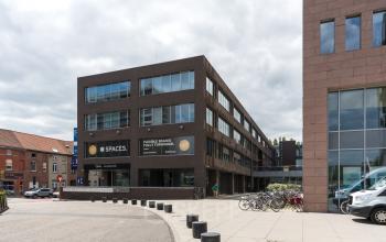 Vooraanzicht van het kantoor te huur gelegen op Gaston Crommenlaan 8, Gent Ledeberg. Stijlvol gebouw met fietsenstalling aan de voorkant.