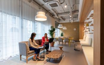 Zakelijke professionals werkend op laptops in moderne kantoorruimte te huur aan Gaston Crommenlaan 8, Gent Ledeberg, met zitbanken, tafels en moderne verlichting.