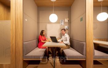 Twee personen in een moderne kantoorruimte aan Gaston Crommenlaan 8, Gent Ledeberg, voeren een vergadering aan een tafel in een gezellige nis. Kantoorruimte te huur in Gent.