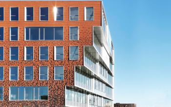 Modern rood bakstenen kantoorgebouw te huur aan het Oktrooiplein 1 in Gent, met grote glazen ramen en een strakke architectuur.