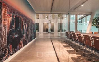 Zicht op moderne vergaderruimte in kantoor te huur op Oktrooiplein 1, Gent. Glazen wand, stijlvolle vergaderstoelen en groot stadsbeeld aan één muur.
