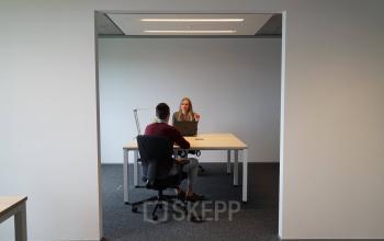 Zakelijke bespreking in een moderne kantoorruimte te huur op Diamantstraat 8, Herentals, met twee personen aan een tafel.