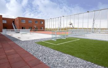 Buitenaanzicht van het gebouw op Diamantstraat 8, Herentals, met sportvelden en open lucht. Kantoorruimte te huur op een strategische locatie.