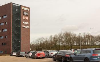 Kantoor te huur op Atealaan 34A, Herentals, zicht op de buitenkant van het gebouw en parkeerplaats vol auto's.