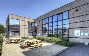 Kantoor te huur op Generaal de Wittelaan 11a, Mechelen Noord, met grote ramen en buitenruimte met picknicktafels.