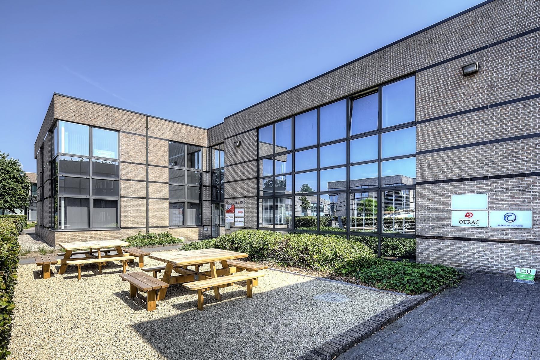 Kantoor te huur op Generaal de Wittelaan 11a, Mechelen Noord, met grote ramen en buitenruimte met picknicktafels.